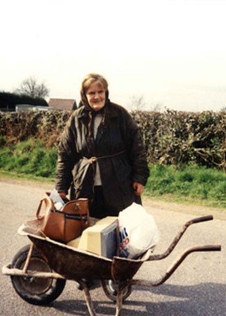 Elderly lady with wheelbarrow full of belongings